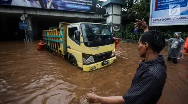 Petugas dibantu warga mendorong truk yang mogok akibat terjebak banjir di terowongan Dukuh Atas, Jakarta, Senin (11/12). Hujan lebat yang mengguyur ibu kota mengakibatkan genangan hingga satu meter di lokasi tersebut. (Liputan6.com/Faizal Fanani)