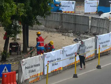 Warga berjalan di samping proyek pelebaran jalur khusus pejalan kaki atau pedestrian di kawasan Sarinah, Jakarta, Rabu (4/7). Pelebaran ini dilakukan untuk menyambut Asian Games 2018. (Merdeka.com/Imam Buhori)