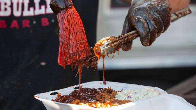 Koki menambahkan saus barbeku pada iga yang sudah dimasak dalam acara drive-thru Scarborough Ribfest 2020 di Toronto, Kanada, 27 September 2020. Pengunjung festival makanan yang digelar dalam format drive-thru itu dapat memesan makanan dari penjual di lokasi dan membawanya pulang. (Xinhua/Zou Zheng)