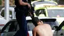 Seorang pria menggunakan telepon genggamnya dekat polisi bersenjata setelah insiden penembakan di Masjid Al Noor, Christchurch, Selandia Baru, Jumat (15/3). (AP Photo/Mark Baker)