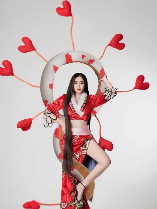 Cropped top lengan panjang berwarna merah, dengan detail bulu putih di bagian kerahnya manis membalut tubuh Aura Kasih bagian atas. Untuk bawahannya, Aura Kasih mengenakan rok dengan slit tinggi memperlihatkan kakinya yang jenjang. Rok ini memiliki detail motif yang serasi dengan atasan yang dikenakan. [Foto: Instagram/aurakasih]