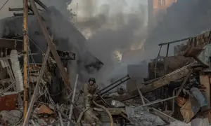 Seorang petugas pemadam kebakaran bekerja di lokasi di samping gedung apartemen bertingkat yang rusak akibat serangan rudal dan pesawat tak berawak besar-besaran Rusia di Kyiv pada Selasa 2 Juni 2026, di tengah invasi Rusia ke Ukraina. (Roman PILIPEY/AFP)