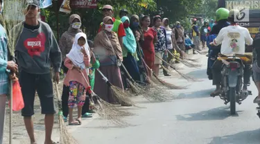 Sejumlah penyapu koin kali Sewo menunggu di sepanjang pinggir jalan, Subang, Jawa Barat, Sabtu (7/1). Mereka menunggu pengendara yang lewat melempar koin ke jalan. (Liputan6.com/Helmi Afandi)