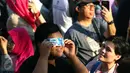 Seorang warga menggunakan plastik air mineral untuk melihat fenomena Gerhana Matahari Total (GMT) menggunakan ponsel di Taman Ismail Marzuki, Jakarta, Rabu (9/3). Fenomena gerhana matahari 90% bisa diamati selama 2,11 menit. (Liputan6.com/Fery Pradolo)
