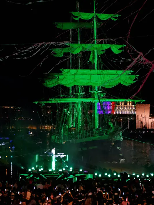Penonton menyambut kedatangan Api Olimpiade di Vieux-Port (Pelabuhan Lama) dengan latar belakang kapal barque Belem dari abad ke-19 Prancis di Marseille, pada tanggal 8 Mei 2024. (Ludovic MARIN/AFP)
