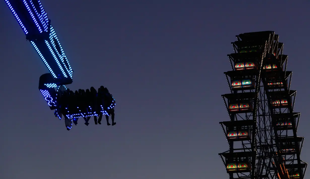 Pengunjung menikmati wahana taman hiburan selama berlangsungnya festival bir Oktoberfest di Munich, 27 September 2018. Festival yang merupakan salah satu acara paling terkenal di Jerman ini sudah ada sejak tahun 1800an. (AP/Matthias Schrader)