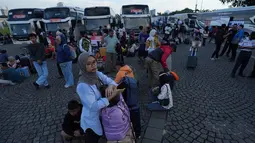 Pemerintah Provinsi DKI Jakarta memberangkatkan peserta mudik gratis 2026 dari Lapangan Monas pada Selasa 17 Maret 2026. Tampak dalam foto, orang-orang menunggu untuk menaiki bus yang akan mengangkut mereka ke kampung halaman untuk merayakan Hari Raya Idul Fitri 1447 Hijriah dalam perjalanan mudik gratis yang diselenggarakan oleh Pemerintah Provinsi Jakarta di Lapangan Monumen Nasional, Selasa 17 Maret 2026. (AP Photo/Achmad Ibrahim)
