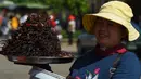 Pedagang Kamboja menjajakan tarantula goreng dan serangga di wilayah Skun, Provinsi Kampong Cham, 4 Desember 2019. Daerah yang kerap dijuluki "Spiderville" tersebut menjadi tempat menarik bagi para turis berburu aping, camilan tradisional dari tarantula ini. (TANG CHHIN Sothy / AFP)