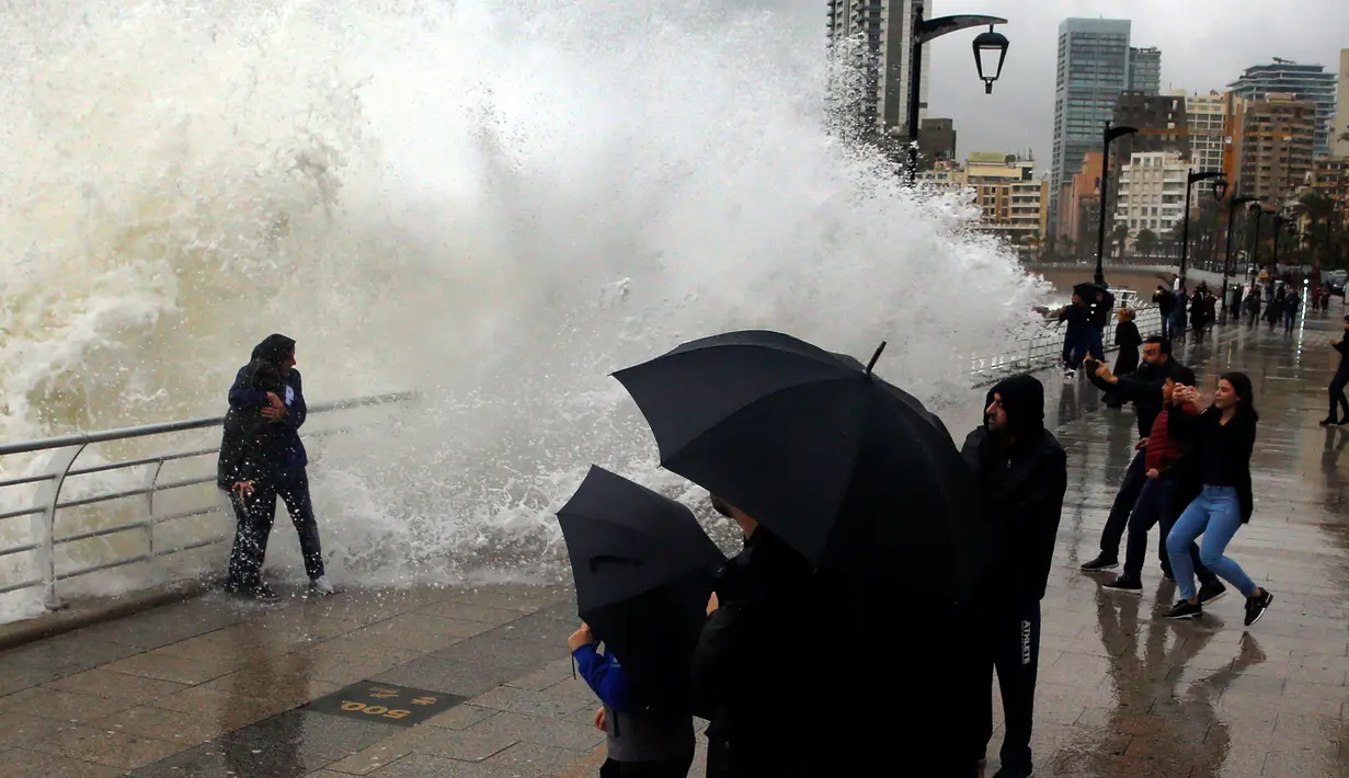 Warga foto didekat ombak besar di Beirut, Lebanon (6/1). Badai kuat di Lebanon membawa suhu dingin dan salju ke pegunungan dan hujan lebat, angin kencang melanda pantai bagian dari negara Mediterania tersebut. (AP Photo/Bilal Hussein)