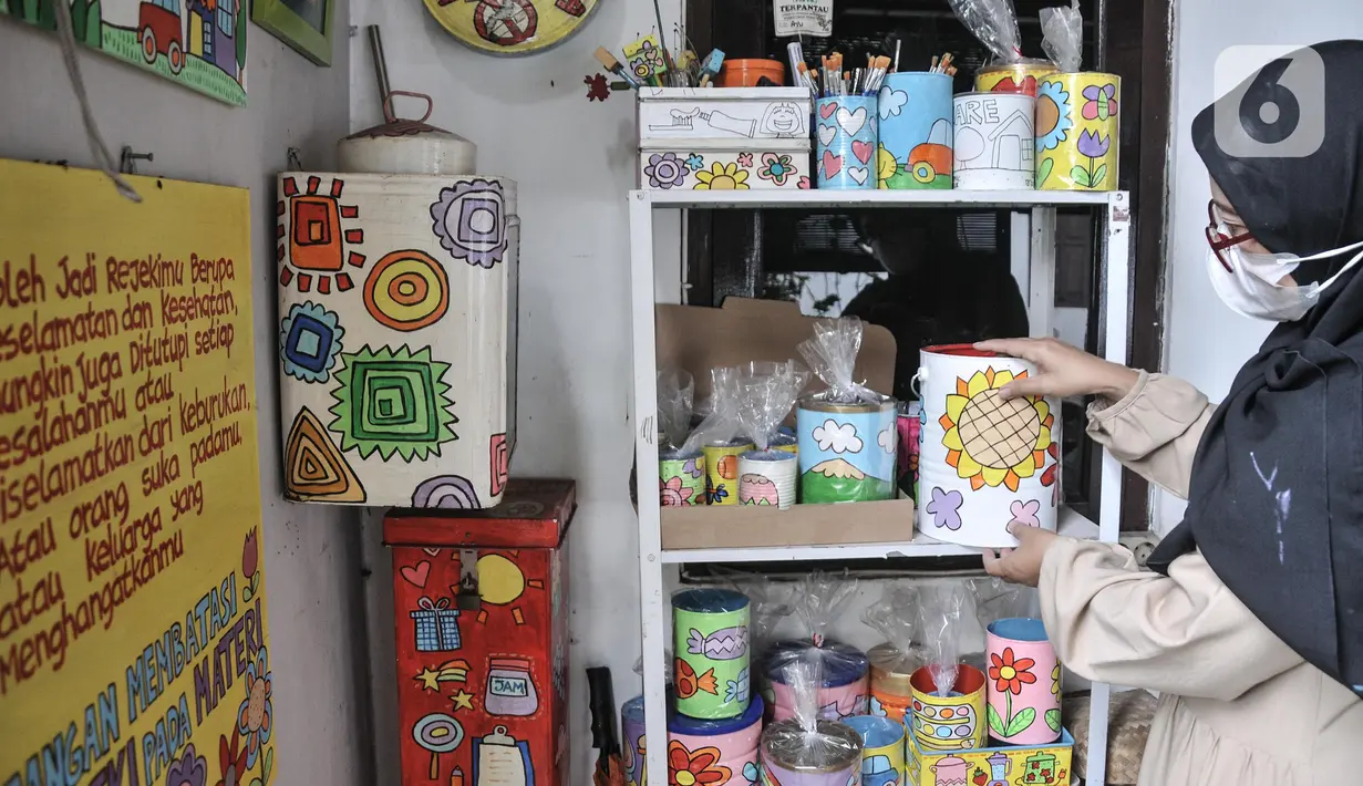 Lani merapikan produk kerajinan dari kaleng bekas yang siap dipasarkan di workshop Kaleng Lani, Tanah Baru, Beji, Depok, Jawa Barat, Minggu (5/6/2022). Perempuan yang sebelumnya berkarir di dunia arsitektur tersebut menggambar berbagai jenis tema yang berkaitan dengan anak-anak dan menjadikan kaleng bekas sebagai tempat pensil, vas bunga, hingga celengan. (merdeka.com/Iqbal S Nugroho)