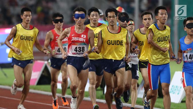 Pelari 5000 meter putra kategori T11 Asian Para Games 2018 saat laga final di SUGBK, Jakarta, Jumat (12/10). Pemandu kategori T11 juga harus memiliki fisik dan kemampuan yang sama atau lebih dari pelari utamanya. (Liputan6.com/Helmi Fithriansyah)