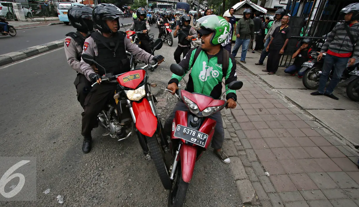 Petugas menghalau salah satu pengemudi ojek online di kawasan Senayan, Jakarta, Selasa (22/3). Pascabentrok ojek online melakukan sweeping dan perusakan terhadap taksi serta bajaj yang melintas di kawasan tersebut. (Liputan6.com/Immanuel Antonius)