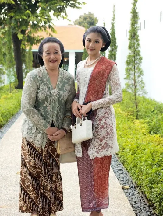 Mengenakan kebaya putih lengan panjang brokat senada dengan warna hand bag putih Diornya. Erina pun mengenakan selendang dan bawahan kain batik warna senada.  [@erinagudono]