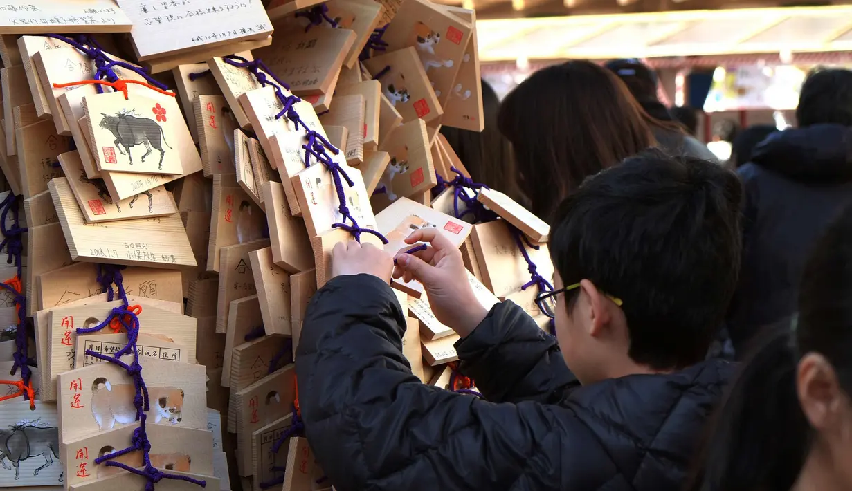 Para pelajar menaruh papan Ema berisi harapan mereka di Kuil Yushima Tenmangu, Tokyo, Jepang, (7/1). Para siswa dan orang tua di Tokyo ramai-ramai mengunjungi Kuil Yushima Tenmangu untuk berdoa sebelum ujian sekolah dimulai. (AFP Photo/Kazuhiro Nogi)
