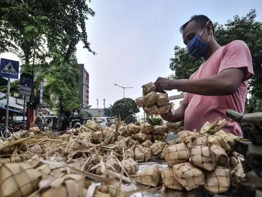 Pedagang menyiapkan ketupat matang di pinggir jalan kawasan Rawamangun, Jakarta, Senin (19/7/2021). Jelang Hari Raya Idul Adha, pedagang ketupat matang atau siap saji musiman mulai ramai menjajakan makanan khas Lebaran tersebut di pinggir jalan kawasan Rawamangun. (merdeka.com/Iqbal S. Nugroho)