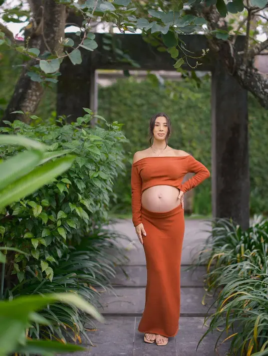 Ia mengenakan long sleeve sabrina dan rok berwarna terracotta sembari pamer baby bump [instagram/namasaweddings]