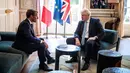 Presiden Prancis Emmanuel Macron berbincang dengan PM Inggris, Boris Johnson dalam kunjungan kenegaraan di Istana Elysee, Paris, Kamis (22/8/2019). Dalam pertemuan, Johnson tertangkap kamera bercanda ke arah kamera dan meletakkan kakinya di meja kopi. (Christophe Petit Tesson, Pool via AP)