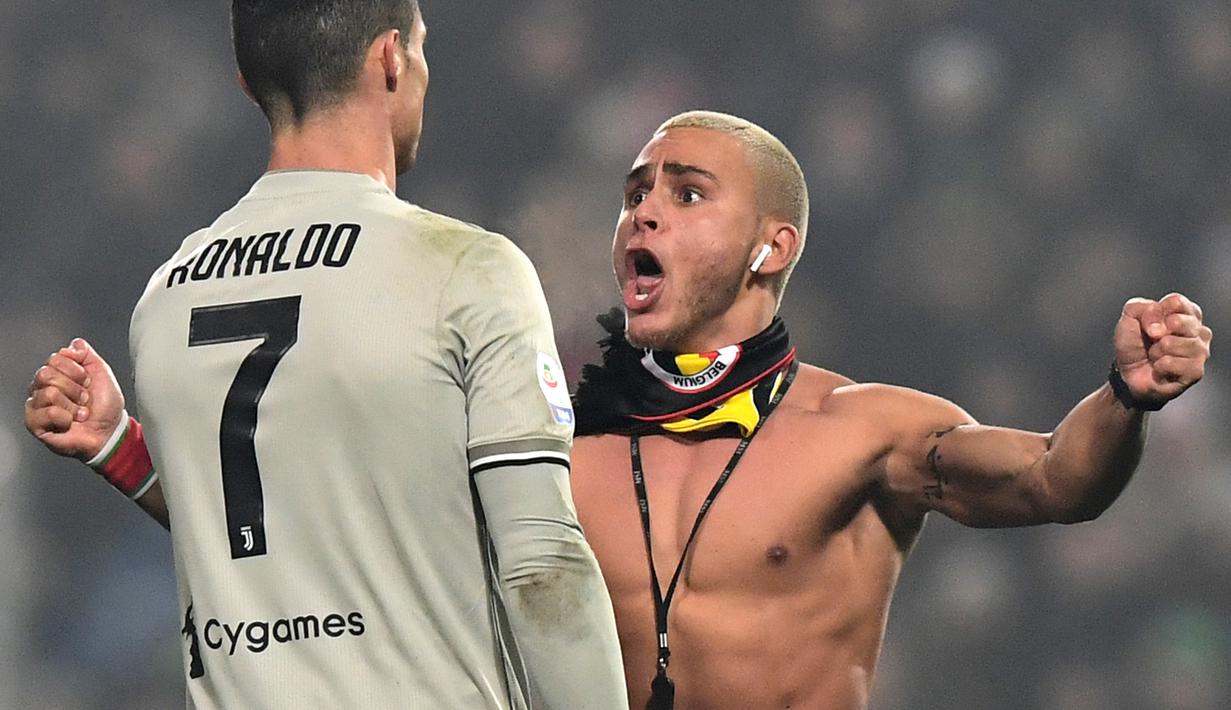 Suporter Juventus yang masuk ke lapangan dan menghampiri Cristiano Ronaldo pada laga lanjutan Serie A yang berlangsung di stadion Mapei, Reggio Emilia, Senin (11/2). Juventus menang 3-0 atas Sassuolo. (AFP/Miguel Medina)