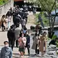 Orang-orang yang memakai masker berjalan di sepanjang sungai Cheonggye di Seoul, Korea Selatan, Jumat (15/4/2022). Korea Selatan atau Korsel akan menghapus sebagain besar pembatasan covid-19 mulai pekan depan menyusul lonjakan kasus Omicron yang mulai berkurang. (Jung Yeon-je / AFP)