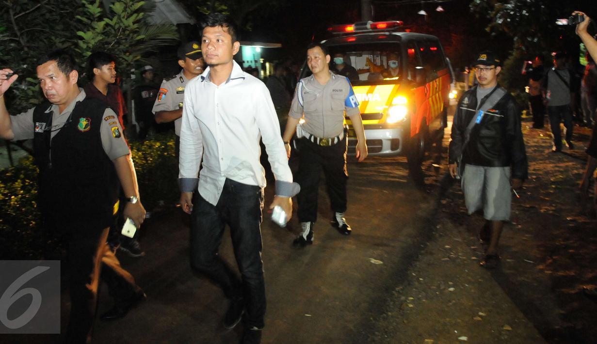 Petugas mengawal ambulan yang berisi mayat terduga teroris di Setu, Tangerang Selatan, Banten, Rabu (21/12). Densus 88 terlibat baku tembak yang akhirnya menewaskan tiga orang terduga teroris. (Liputan6.com/Helmi Afandi)