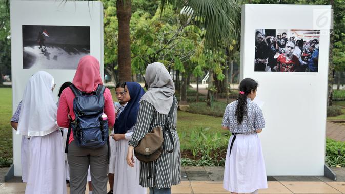 Siswa SD Negeri Menteng 01 mengamati karya foto yang dipamerkan dalam pameran fotografi Rekam Jakarta di Taman Menteng, Kamis (29/8/2019). Kegiatan tersebut dalam rangka edukasi bagi siswa mengenal profesi foto jurnalistik. (merdeka.com/Iqbal S Nugroho)