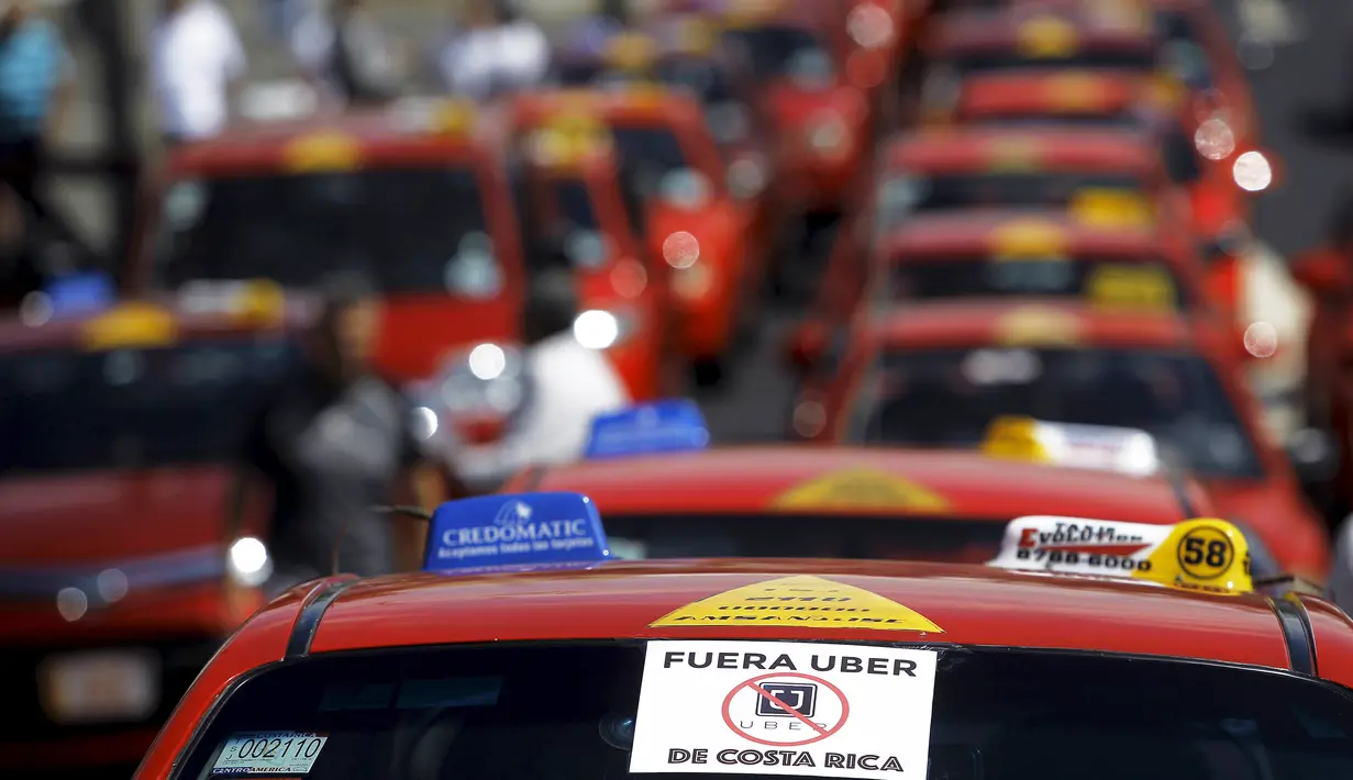 Stiker bertuliskan "Uber, keluar dari Kosta Rika" tertempel di kaca sebuah taksi saat unjuk rasa di San Jose, Senin (1/2).  Sejumlah sopir taksi melakukan protes terhadap taksi Uber yang mulai beroperasi di Kosta Rika. (REUTERS/Juan Carlos Ulate)