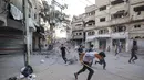 Orang-orang berlari mencari perlindungan setelah serangan Israel yang menargetkan sebuah bangunan di kamp pengungsi Palestina Bureij di Jalur Gaza tengah pada 19 Oktober 2025. (Eyad BABA/AFP)