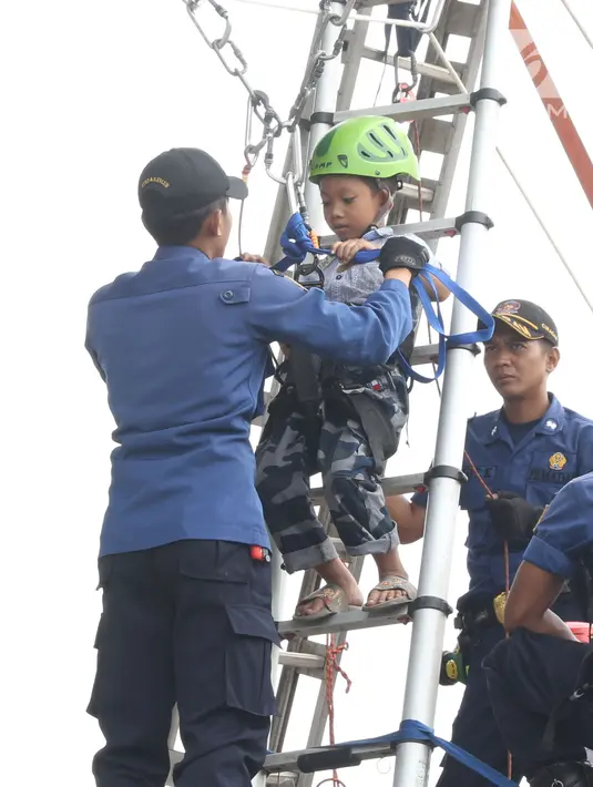 Petugas Damkar PB mengecek kesiapan dan keamanan anak-anak yang akan bermain Flying Fox di kawasan Monumen Nasional, Jakarta, Selasa (1/1). Permainan digelar untuk menambah pelayanan kepada warga yang berlibur. (Liputan6.com/Helmi Fithriansyah)