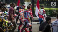 Presiden Joko Widodo berjalan bersama para pembalap MotoGP keluar dari Istana Merdeka, Jakarta Pusat, Rabu (16/3/2022). Jokowi melepas iring-iringan pembalap berkeliling di jalan utama ibu kota sebelum para pembalap berlaga di MotoGP Mandalika yang berlangsung pekan ini. (Liputan6.com/Faizal Fanani)