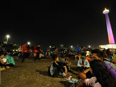 Pengunjung duduk duduk di halaman Monumen Nasional, Jakarta, Sabtu (31/12). Dengan alasan keamanan, Pemprov DKI Jakarta membatalkan panggung hiburan malam pergantian tahun di kawasan Monumen Nasional. (Liputan6.com/Helmi Fithriansyah)