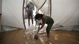 Air juga sempat menggenangi tenda yang menjadi tempat berlindung sementara bagi warga yang kehilangan rumah akibat konflik antara Israel dan Hamas di Gaza sejak Oktober 2023. Tampak dalam foto, Saja Fayyad, 7 tahun, mencoba membersihkan air dari tenda keluarganya yang terendam banjir di kamp sementara untuk warga Palestina yang mengungsi setelah hujan deras di Deir al-Balah, Jalur Gaza tengah, Selasa 25 November 2025. (AP Photo/Abdel Kareem Hana)