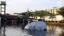 Sebuah mobil terparkir di jalanan yang terendam banjir rob di kawasan Muara Baru, Penjaringan, Jakarta Utara, Kamis (7/12). Rob tinggi membuat tanggul tidak mampu menahan air laut sehingga membanjiri jalanan. (Liputan6.com/Johan Tallo)