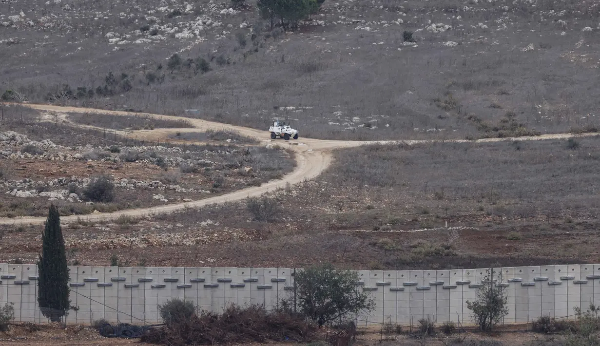 Israel berdalih bahwa tembok itu bagian dari rencana militer yang lebih luas, yang pembangunannya dimulai pada 2022 lalu. Tampak dalam foto yang diambil dari Israel, menunjukkan kendaraan Pasukan Sementara PBB di Lebanon (UNIFIL) yang sedang berpatroli di sisi Lebanon dari perbatasan yang memisahkan Israel utara dan Lebanon selatan pada 16 November 2025. (Jalaa MAREY/AFP)