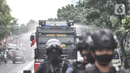 Petugas kepolisian menggunakan kendaraan meriam air saat menyemprotkan cairan disinfektan di Kawasan Petamburan, Jakarta, Minggu (22/11/2020). (merdeka.com/Iqbal S. Nugroho)