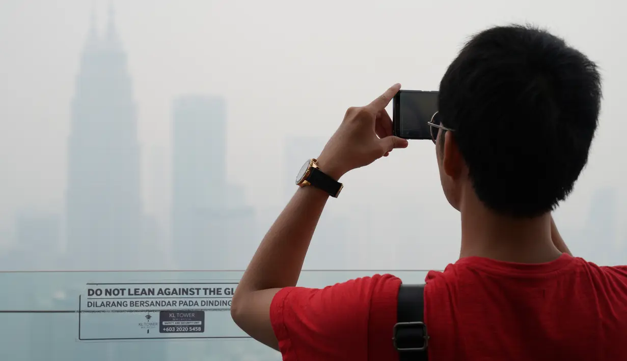 Wisatawan mengambil gambar dari Kuala Lumpur Tower saat kabut asap pekat menyelimuti Kuala Lumpur, Malaysia, Jumat (13/9/2019). Kabut asap membuat kualitas udara memburuk. (AP Photo/Vincent Thian)