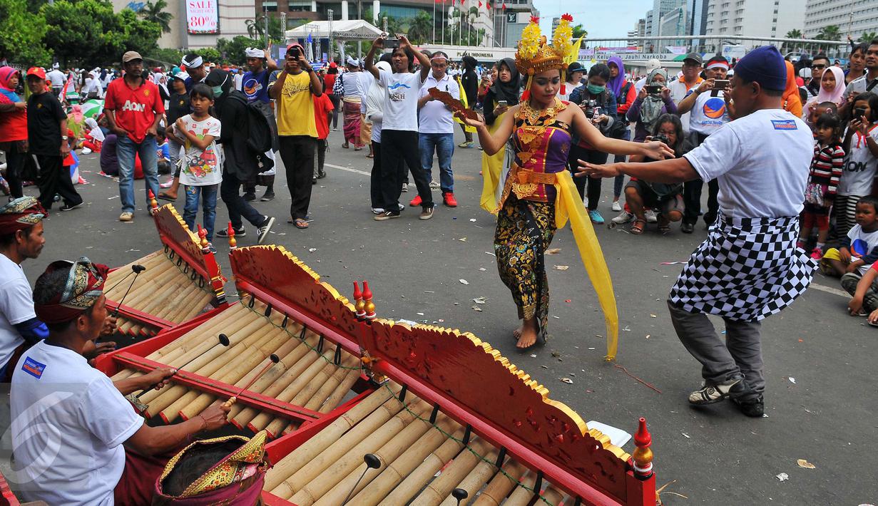 Seorang peserta ikut menari Tari Pendet khas Bali dalam parade kebudayaan bertajuk 'Kita Indonesia' di kawasan Bundaran HI, Jakarta, Minggu (4/12). Para peserta Parade Kebudayaan tampak antusias menyaksikan tarian itu. (Liputan6.com/Angga Yuniar)