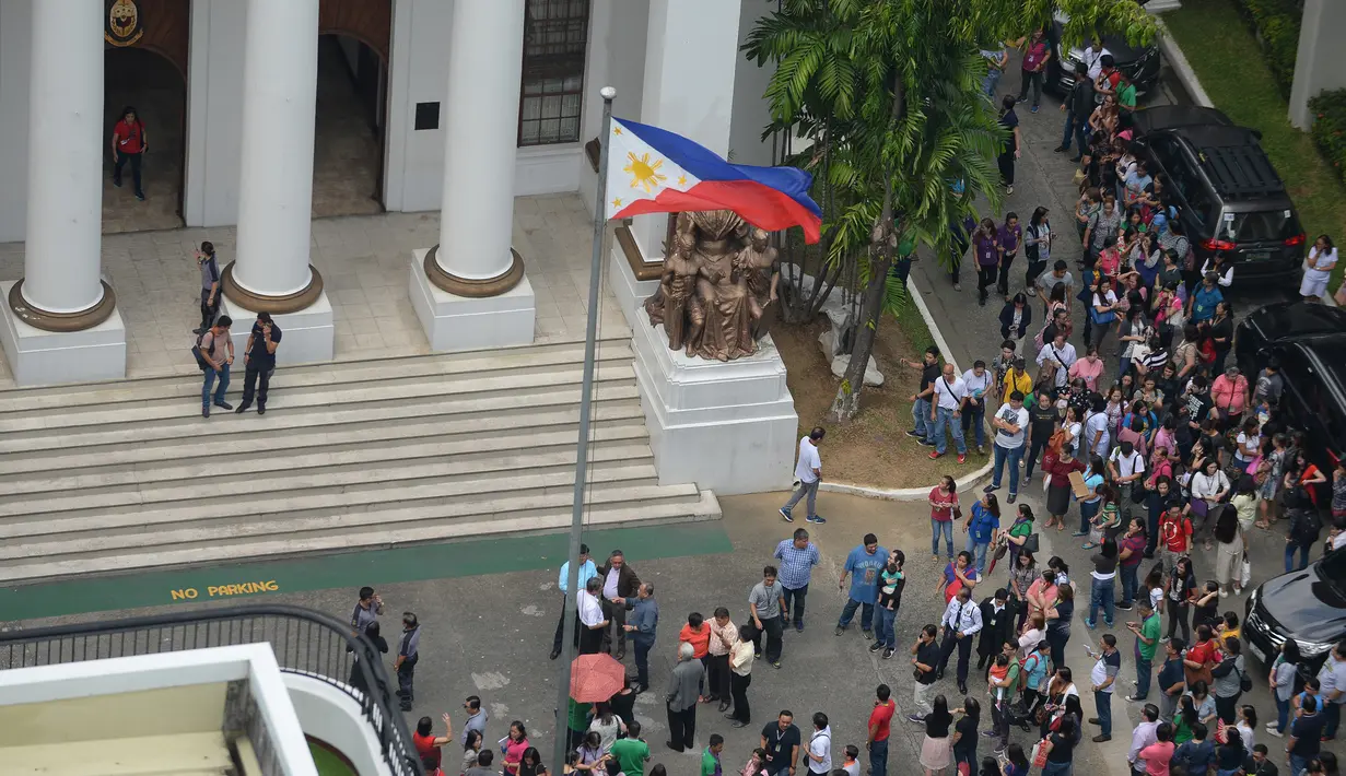 Pegawai pengadilan berkumpul di depan gedung setelah gempa melanda Manila, Filipina (11/8). Gempa bertenaga 6,2 skala Richter mengguncang wilayah selatan ibukota Filipina yang menyebabkan bangunan di Manila rusak. (AFP Photo/Ted Aljibe)