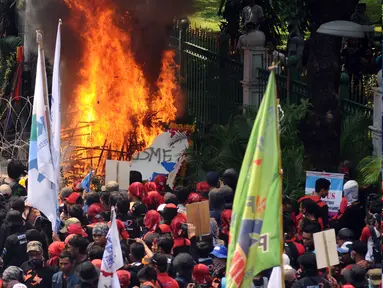 Sebuah karangan bunga dibakar massa saat aksi perayaan MayDay di Jalan Medan Merdeka Barat, Senin (5/1). Ribuan massa buruh turun ke jalan dalam perayaan Hari Buruh Internasional. (Liputan6.com/Helmi Fithriansyah)