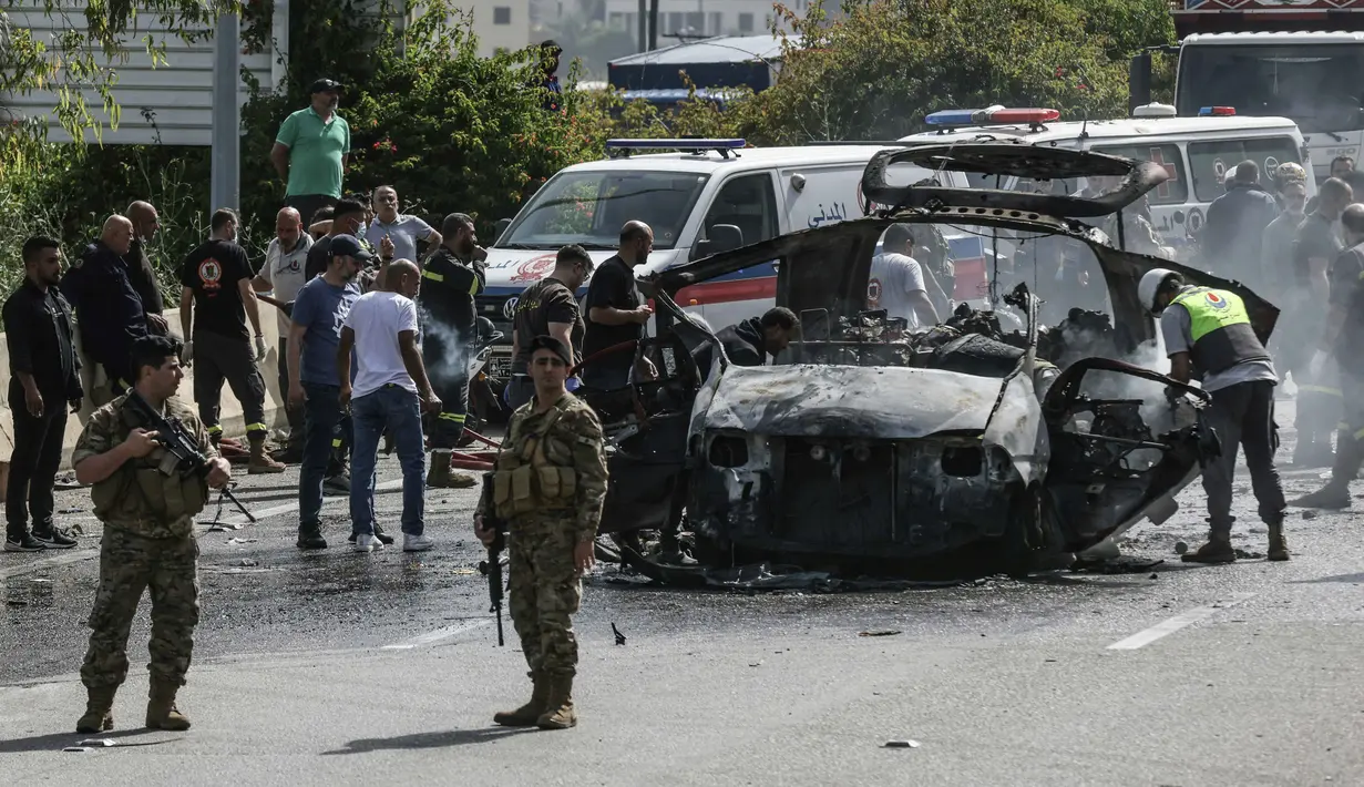 Petugas pertolongan pertama bekerja di sekitar kendaraan yang menjadi sasaran serangan pesawat tak berawak Israel di jalan raya dekat kota Jiyeh, Selatan Beirut, pada Rabu 13 Mei 2026. (MAHMOUD ZAYYAT/AFP)