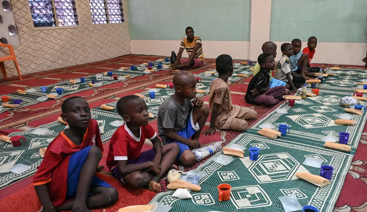 Anak-anak muslim menunggu waktu berbuka puasa di hari kedua bulan suci Ramadhan di sebuah masjid di Treicheville, komune populer di Abidjan pada 24 Maret 2023. (AFP/Sia KAMBOU)
