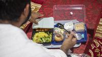 Jemaah makan dalam kamp saat melaksanakan rangkaian ibadah haji di Kota Suci Makkah, Arab Saudi, Kamis (30/7/2020). Hanya sekitar seribu jemaah yang diizinkan untuk melakukan ibadah haji tahun ini karena pandemi COVID-19. (Saudi Ministry of Media via AP)