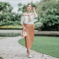 Tampilan feminin yang stylish, padukan long sleeve dengan satin flare skirt warna peach. Makin stylish dengan cardigan yang diikat di pundak. (Instagram/jscmila).