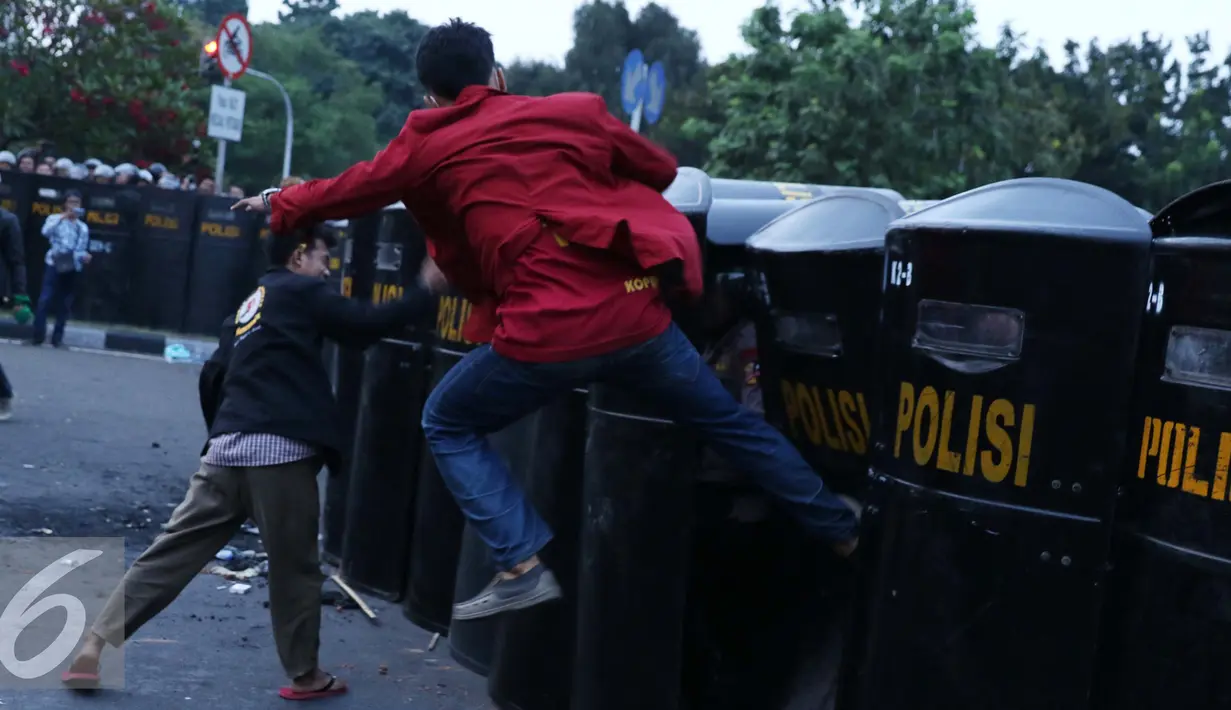 Seorang mahasiswa menendang tameng polisi yang berjaga saat unjuk rasa di Jalan Medan Merdeka Barat, Jakarta, Kamis (20/10). Mahasiswa menagih janji Nawacita pemerintahan Jokowi-JK. (Liputan6.com/Gempur M Surya)