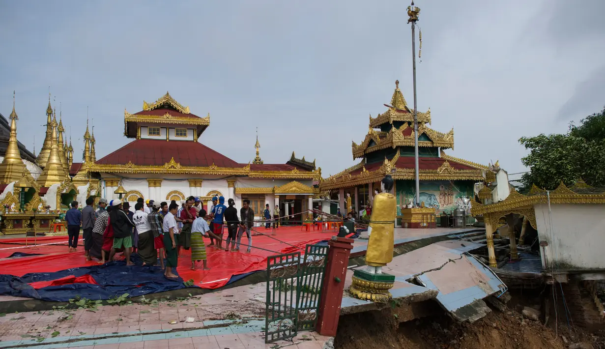 Warga menarik patung Buddha akibat hujan dan tanah longsor yang merusak pagodha di puncak bukit Kyeik Than Lan, Myanmar (18/6). Beberapa wilayah di negara bagian Mon, menghadapi banjir akibat hujan deras sejak akhir pekan lalu. (AFP PHOTO / Ye Aung Thu)