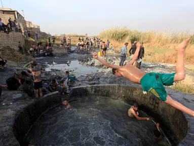 Seorang tentara Irak melompat ke kolam belerang di Hammam al-Ali, Mosul, Irak, (9/11). Di tengah perang melawan ISIS, mereka melepaskan penat dan lelah dengan berenang di Kolam belerang. (REUTERS/Alaa Al-Marjani)