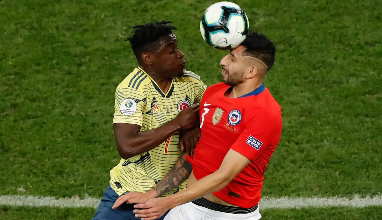 Pemain timnas Cile, Guillermo Maripan berebut bola dengan pemain Kolombia, Duvan Zapata pada perempat final Copa America 2019 di Arena Corinthians, Jumat (29/6/2019). Cile melaju ke semifinal Copa America 2019 setelah menundukkan Kolombia, 5-4, lewat adu penalti. (AP/Nelson Antoine)