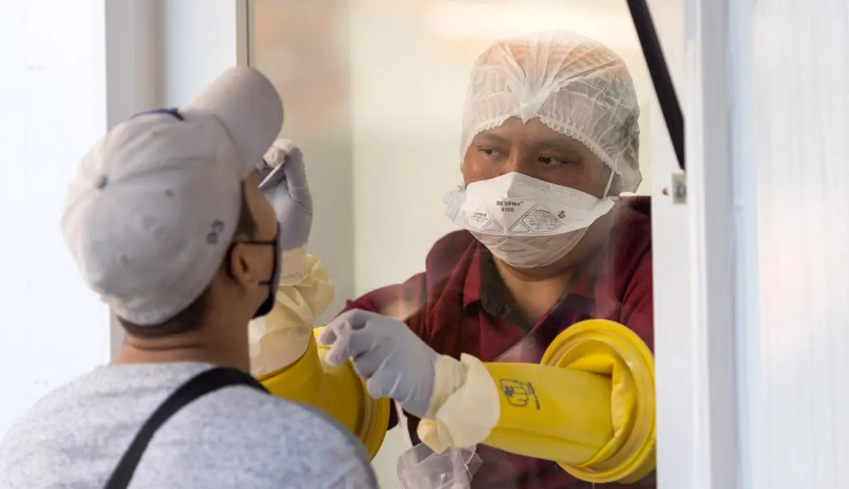 Seorang petugas medis melakukan tes usap hidung saat uji virus corona COVID-19 bagi pekerja perhotelan dan pariwisata di Jalan Khao San, Bangkok, Thailand, Kamis (6/1/2022). (Jack TAYLOR/AFP)