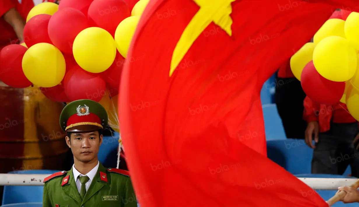 Seorang polisi berjaga di antara kibaran bendera Vietnam saat laga semifinal Piala AFF 2016 melawan Timnas Indonesia di Stadion My Dinh, Hanoi, Kamis (7/12/2016). (Bola.com/Peksi Cahyo) 