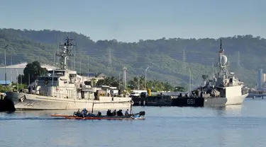Lano cadik berlayar melewati kapal-kapal Angkatan Laut Indonesia di pangkalan angkatan laut di Banyuwangi, Provinsi Jawa Timur, Sabtu (24/4/2021). Militer melanjutkan operasi pencarian kapal selam KRI Nanggala 402 yang hilang pada 21 April saat latihan di lepas pantai Bali. (SONNY TUMBELAKA/AFP)