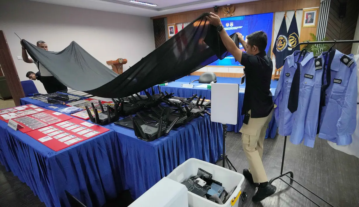 Mereka diringkus di kawasan Babakan Madang, Kabupaten Bogor, karena diduga menyalahgunakan izin tinggal dan diduga menjalankan praktik online scam atau penipuan daring. Tampak dalam foto, petugas Imigrasi menutupi barang bukti yang disita dari warga negara Jepang yang diduga terlibat dalam sindikat penipuan daring (online), di Bogor, Jawa Barat, Rabu 4 Maret 2026. (AP Photo/Achmad Ibrahim)